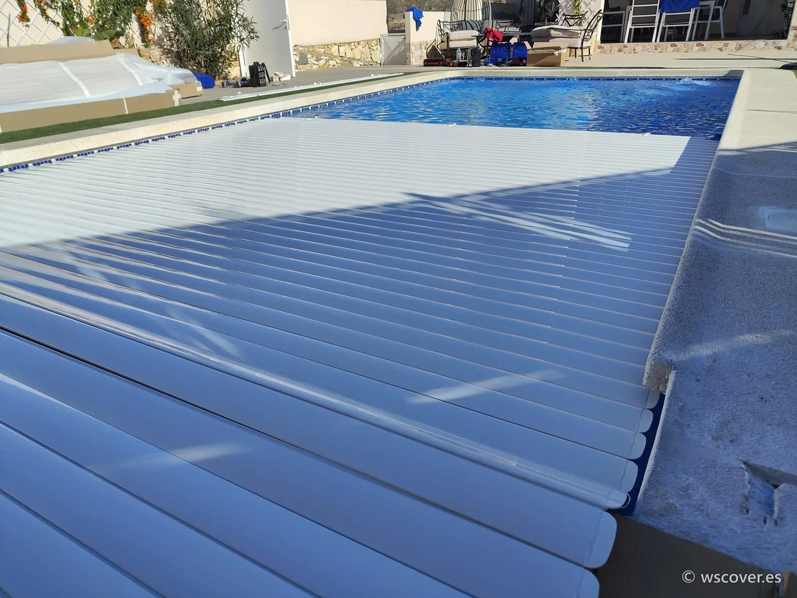White automatic slatted cover half open over the pool