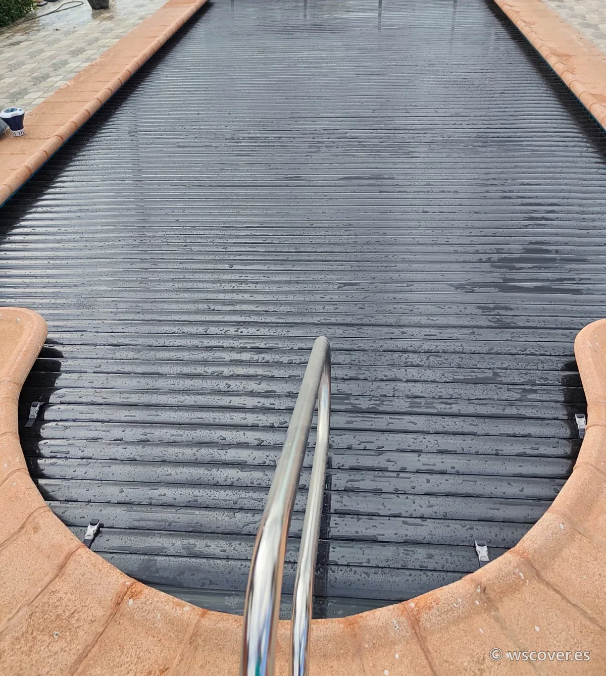 Dark automatic slatted cover on a pool with a Roman-end step
