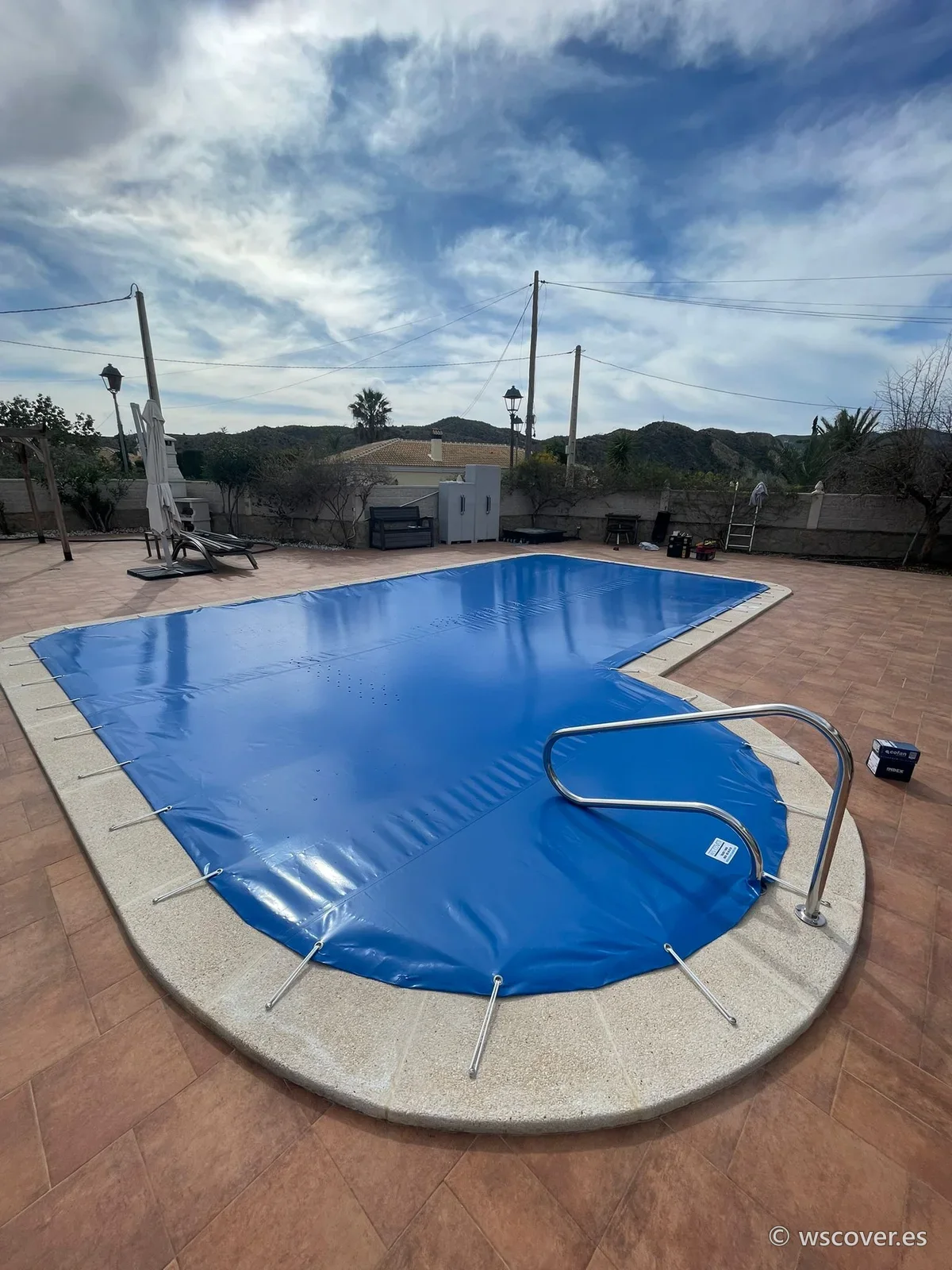 Winter PVC cover on an L-shaped pool with a ladder