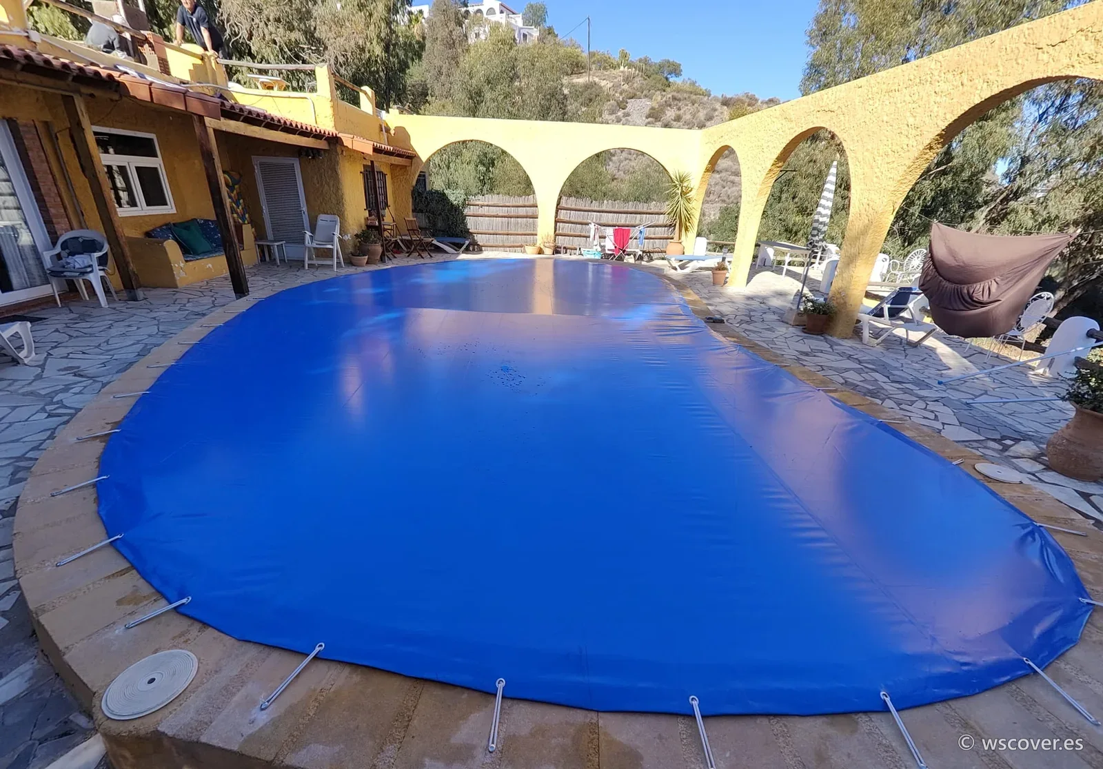 Winter PVC cover on a free-form pool beside an archway