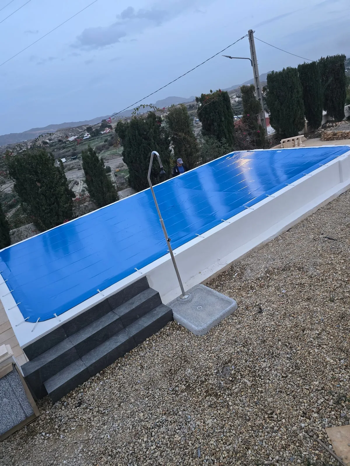Cubierta PVC de invierno sobre piscina elevada, anclada con tensores al perímetro