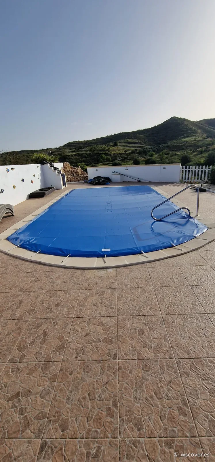 Cubierta PVC de invierno sobre piscina rectangular con escalera, con la montaña al fondo